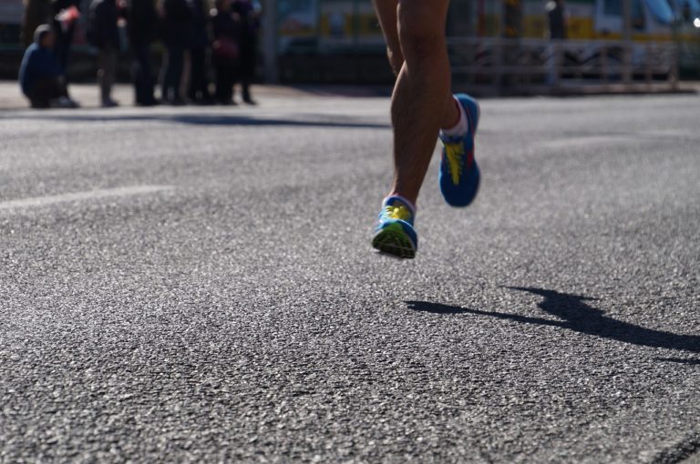 The shadow of a marathon runner running on the street.