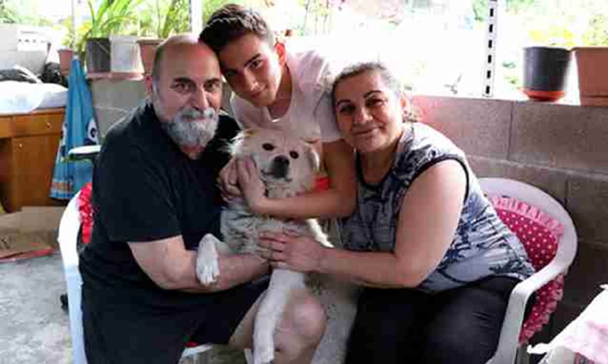 A family with a white dog sitting on a chair.