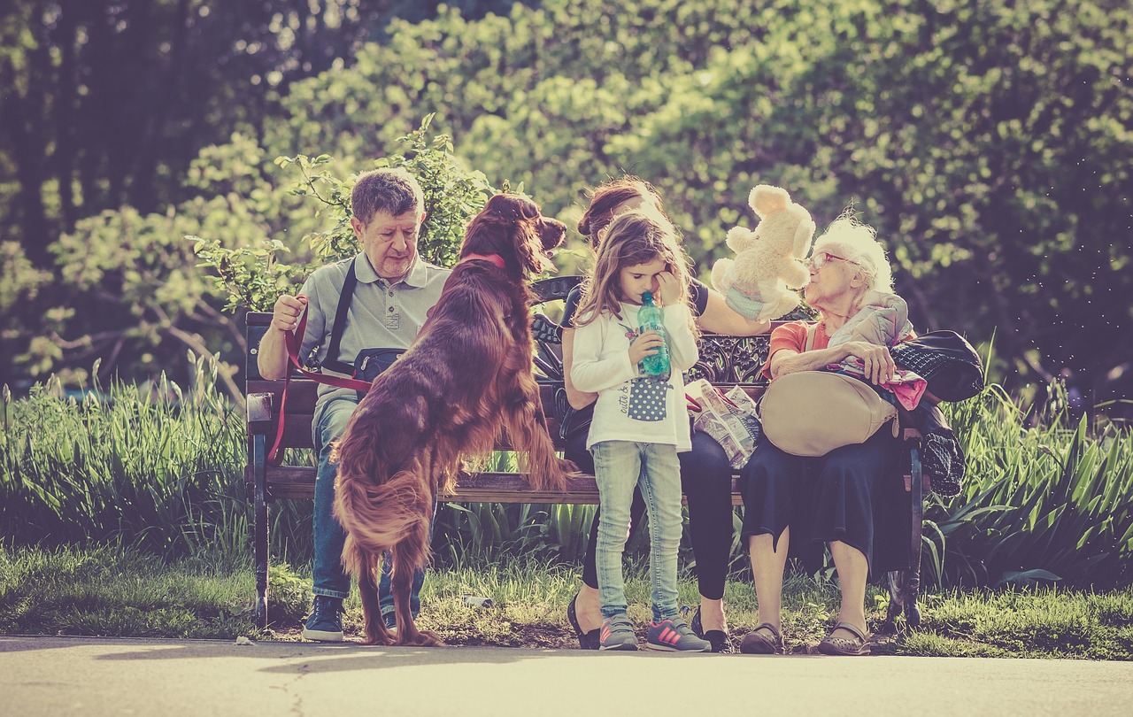 A group of people sitting on a bench with a dog.